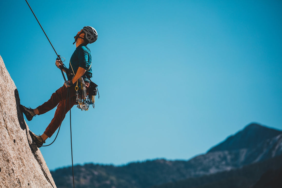 Local guide rappelling on a sunny day with Andean mountains in the background