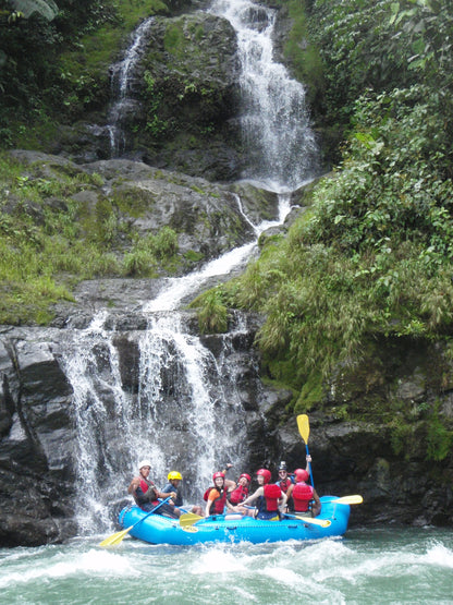 Group of people rafting near a waterfall in a lush green forest in the Pacuare section